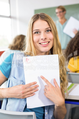 Beautiful female student pointing at paper