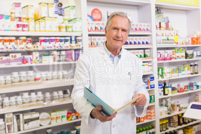 Smiling senior pharmacist holding notebooks