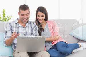 Couple using laptop for video conference on sofa