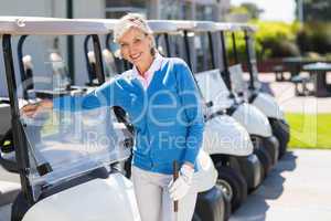 Female golfer beside golf buggy