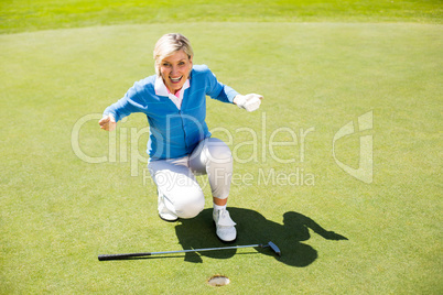 Excited lady golfer cheering on putting green