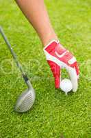 Golfer placing golf ball on tee