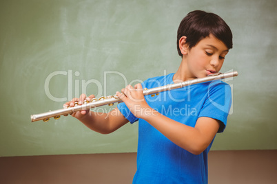 Little boy playing flute in classroom