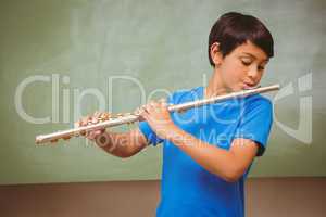 Little boy playing flute in classroom
