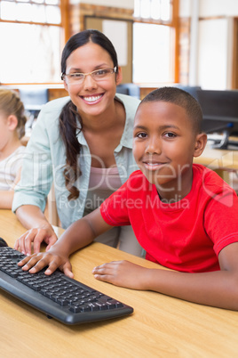 Cute pupil in computer class with teacher