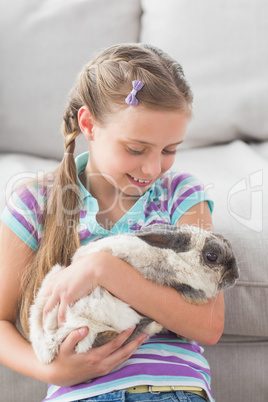 Girl holding rabbit in living room