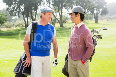 Golfing friends smiling and holding clubs