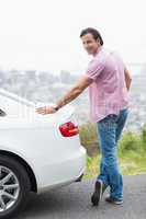 Smiling man standing next to his car