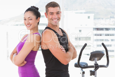 Fit couple smiling at camera with arms crossed