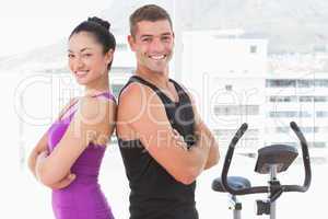 Fit couple smiling at camera with arms crossed