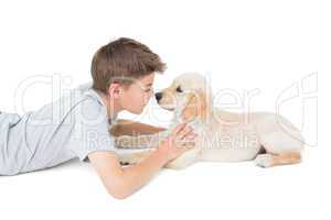 Boy rubbing nose with dog over white background