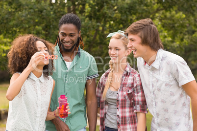 Happy friends in the park blowing bubbles