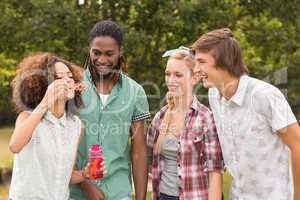 Happy friends in the park blowing bubbles