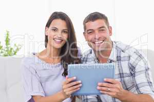 Happy couple holding digital tablet at home