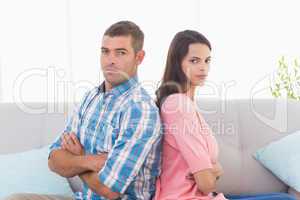 Angry couple sitting arms crossed on sofa