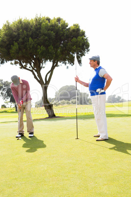 Golfer swinging his club with friend