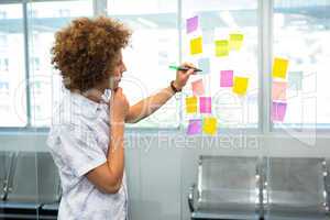Creative businessman writing on adhesive note