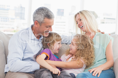 Parents looking at children hugging at home