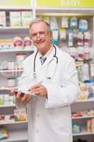 Smiling senior doctor writing on clipboard