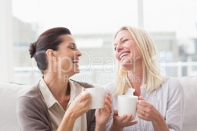 Women gossiping while having coffee in living room