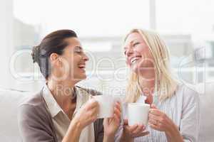 Women gossiping while having coffee in living room