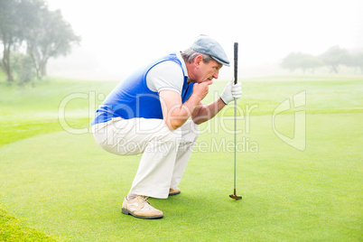 Serious golfer kneeling on the putting green