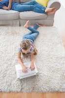 Girl using laptop while lying on rug at home