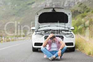 Stressed man sitting after a car breakdown at the side of the ro