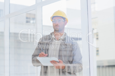 Architect writing on clipboard in office