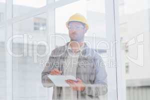 Architect writing on clipboard in office