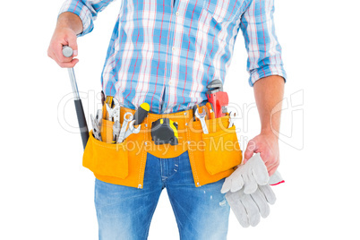 Midsection of handyman holding hammer and gloves