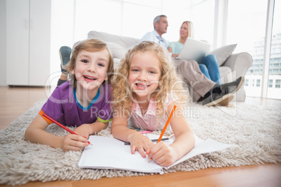 Children drawing on papers while parents sitting on sofa