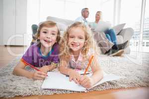 Children drawing on papers while parents sitting on sofa