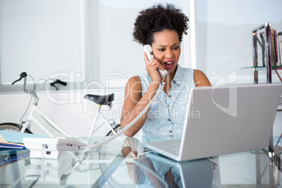 Casual young woman using telephone and laptop