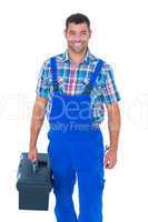 Happy handyman in coveralls carrying toolbox