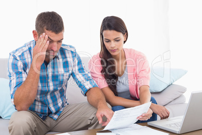 Couple reading bill while calculating home finances