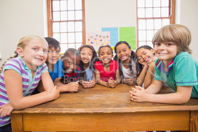 Cute pupils smiling at camera in classroom