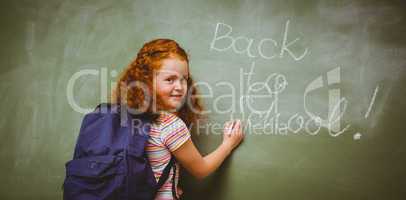 Portrait of cute little girl writing on blackboard