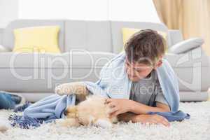 Boy playing with puppy lying on rug