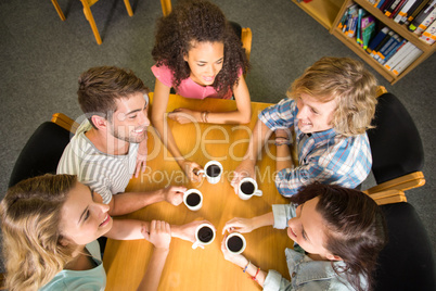 College students holding coffee mugs on table