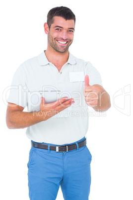 Smiling male handyman with clipboard gesturing thumbs up