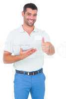 Smiling male handyman with clipboard gesturing thumbs up