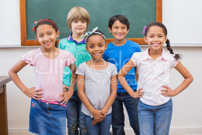 Cute pupils smiling at camera in classroom