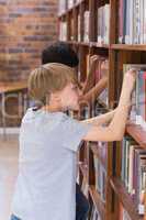 Cute pupils looking for books in library