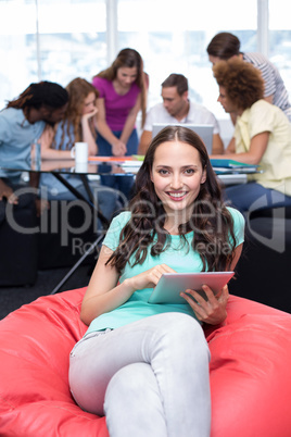 Student using digital tablet with friends in background