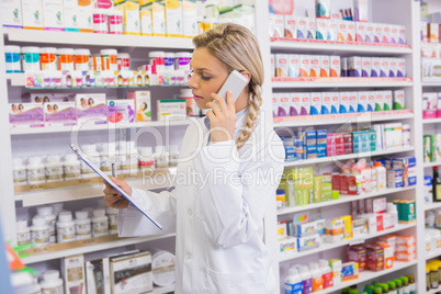 Pharmacy intern phoning while reading clipboard
