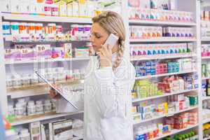 Pharmacy intern phoning while reading clipboard