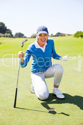 Excited lady golfer cheering on putting green