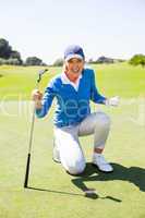 Excited lady golfer cheering on putting green