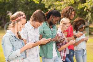 Happy friends in the park using their phones